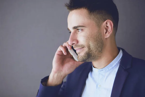 Jungunternehmer sitzt isoliert auf grauem Hintergrund. — Stockfoto