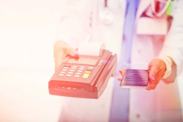 Il dottore tiene in mano il terminale di pagamento. Pagare per l'assistenza sanitaria. Dottore. — Foto Stock