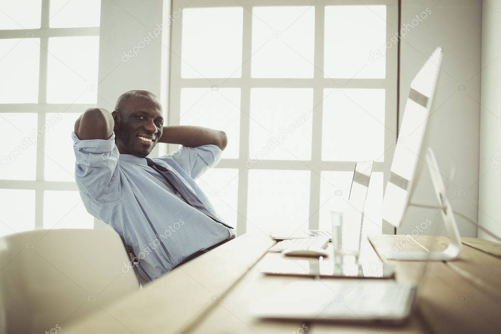 African american businessman on headset working on his laptop