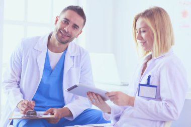 Yakışıklı doktor genç bayan doktorla konuşuyor ve ofisinde otururken notlar alıyor..