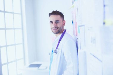 Genç ve kendinden emin erkek doktor portresi tıp ofisinde duruyor..