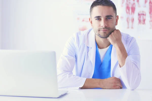 Portrait of a male doctor with laptop sitting at desk in medical office. — Stock Photo, Image