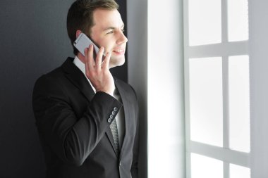 Modern ofiste cep telefonuyla konuşan yakışıklı iş adamı..