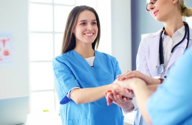 Doktorlar ve hemşireler tıbbi bir ekipte el ele tutuşuyorlar.