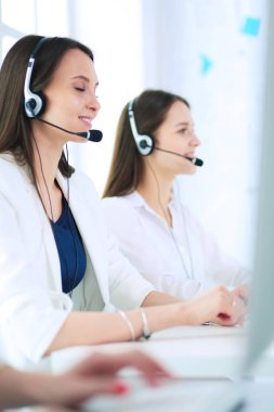 Ofisinde kulaklık ve bilgisayarla gülümseyen iş kadını ya da yardım hattı operatörü