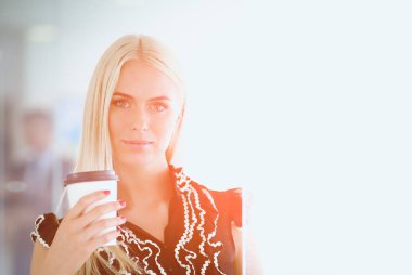 Ofiste bir fincan kahve ayakta tutan işkadını .