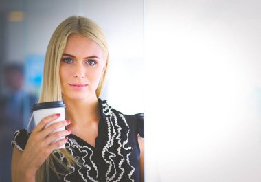 Ofiste bir fincan kahve ayakta tutan işkadını .