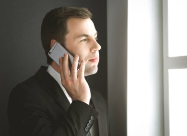 Modern ofiste cep telefonuyla konuşan yakışıklı iş adamı..