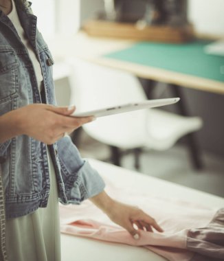 Moda tasarımcısı kadın stüdyoda tasarımları üzerinde çalışıyor.