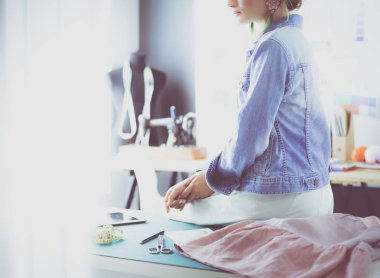 Moda tasarımcısı kadın stüdyoda tasarımları üzerinde çalışıyor.