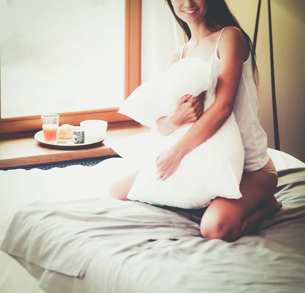 Ung kvinna sitter i sängen med en kopp mjölk — Stockfoto