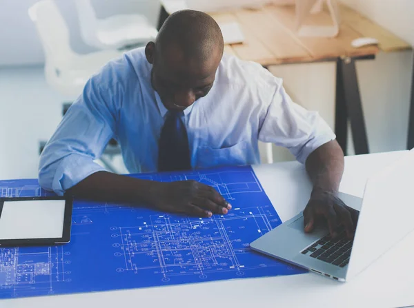 Африканский американский архитектор, работающий с компьютером и чертежами в офисе — стоковое фото