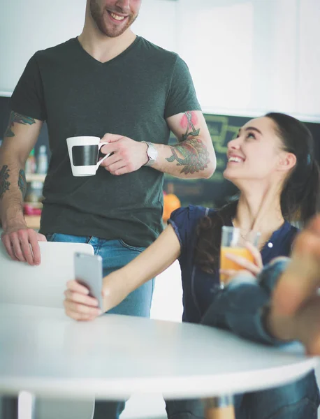 Pareja feliz usando smartphone sentado en la cocina — Foto de Stock