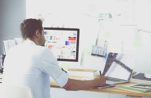 Porträt eines jungen Designers, der im Grafikstudio vor Laptop und Computer sitzt, während er online arbeitet. — Stockfoto