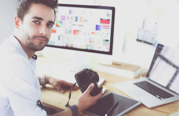 Retrato del joven diseñador sentado en el estudio gráfico frente a la computadora portátil y el ordenador mientras trabaja en línea. — Foto de Stock