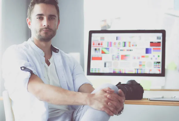 Retrato del joven diseñador sentado en el estudio gráfico frente a la computadora portátil y el ordenador mientras trabaja en línea. —  Fotos de Stock