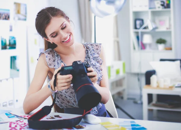 Portret van lachende jonge vrouw met camera zitten in loft appartement — Stockfoto