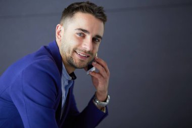 Gri arka planda yalnız oturan genç iş adamı.