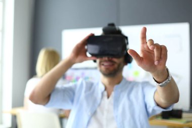 Genç erkek yazılım programcısı ofiste üç boyutlu sanal gerçeklik gözlükleriyle yeni bir uygulama test ediyor..