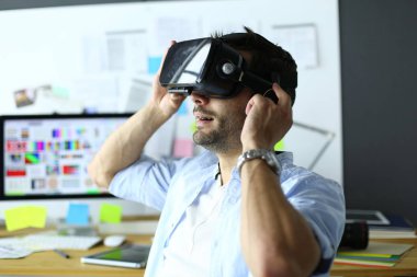 Genç erkek yazılım programcısı ofiste üç boyutlu sanal gerçeklik gözlükleriyle yeni bir uygulama test ediyor..