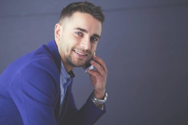 Gri arka planda yalnız oturan genç iş adamı.