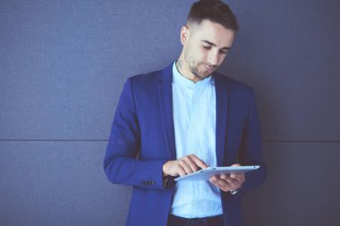 Gri arka planda yalnız oturan genç iş adamı.