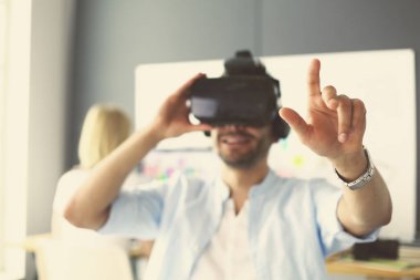 Genç erkek yazılım programcısı ofiste üç boyutlu sanal gerçeklik gözlükleriyle yeni bir uygulama test ediyor..