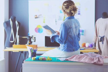 Moda tasarımcısı kadın stüdyoda tasarımları üzerinde çalışıyor.