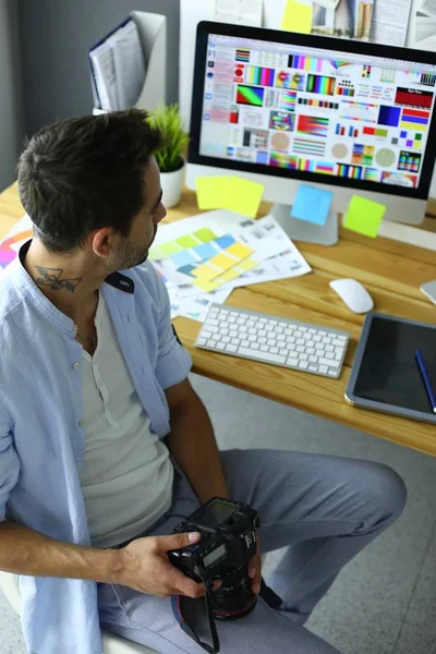 Portret młodego projektanta siedzącego w pracowni graficznej przed laptopem i komputerem podczas pracy online. — Zdjęcie stockowe