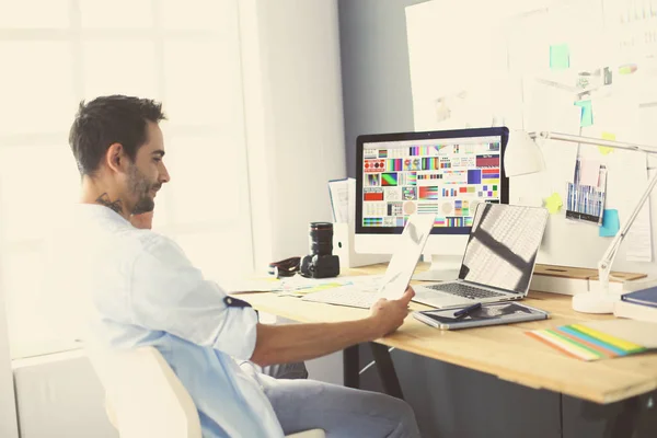 Porträt eines jungen Designers, der im Grafikstudio vor Laptop und Computer sitzt, während er online arbeitet. — Stockfoto