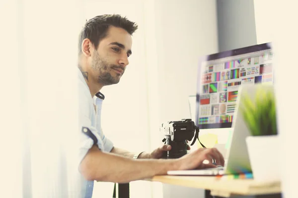 Retrato de jovem designer sentado no estúdio gráfico na frente de laptop e computador enquanto trabalhava online. — Fotografia de Stock