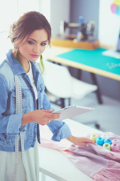 Mulher designer de moda trabalhando com ipad em seus projetos no estúdio — Fotografia de Stock