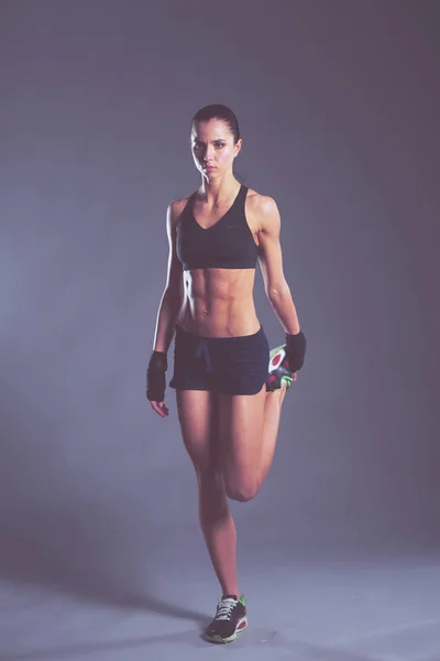 Muskulöse junge Frau posiert in Sportbekleidung vor schwarzem Hintergrund. — Stockfoto