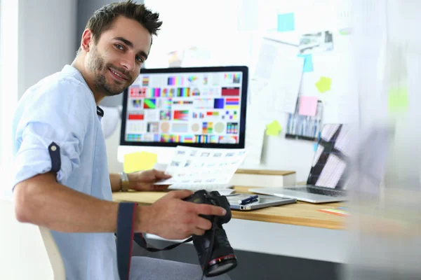 Retrato de jovem designer sentado no estúdio gráfico na frente de laptop e computador enquanto trabalhava online. — Fotografia de Stock