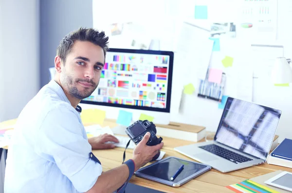Portrait de jeune designer assis dans un studio graphique devant un ordinateur portable et un ordinateur tout en travaillant en ligne. — Photo