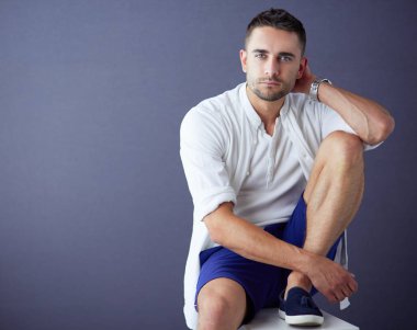 Gri arka planda yalnız oturan genç iş adamı.