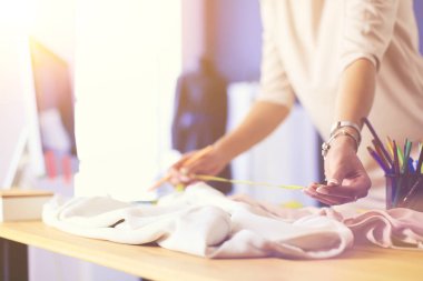 Moda tasarımcısı kadın stüdyoda tasarımları üzerinde çalışıyor.