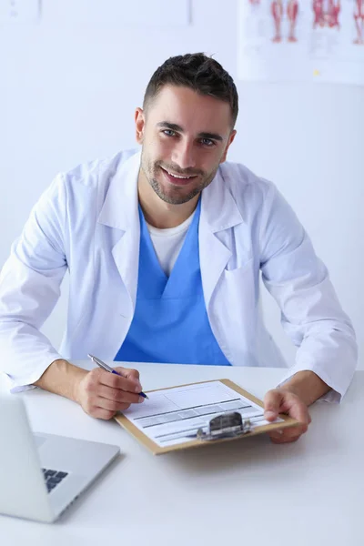 Retrato de un médico varón con portátil sentado en el escritorio en médico — Foto de Stock