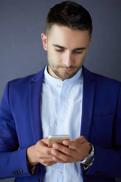 Young businessman sitting isolated on grey background. — Stock Photo, Image