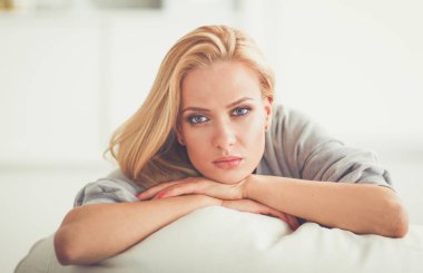 Genç ve güzel bir kadın odasında kanepede oturuyor.