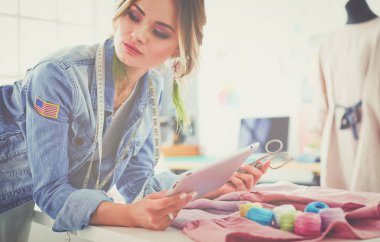 Moda tasarımcısı kadın stüdyoda tasarımları üzerinde çalışıyor.