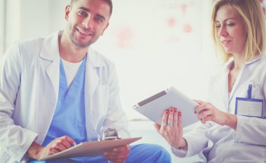 Yakışıklı doktor genç bayan doktorla konuşuyor ve ofisinde otururken notlar alıyor..