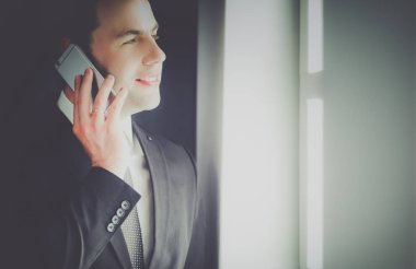 Modern ofiste cep telefonuyla konuşan yakışıklı iş adamı..