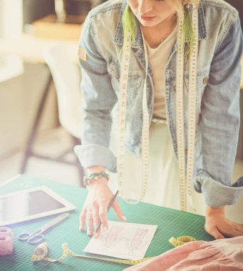 Moda tasarımcısı kadın stüdyoda tasarımları üzerinde çalışıyor.