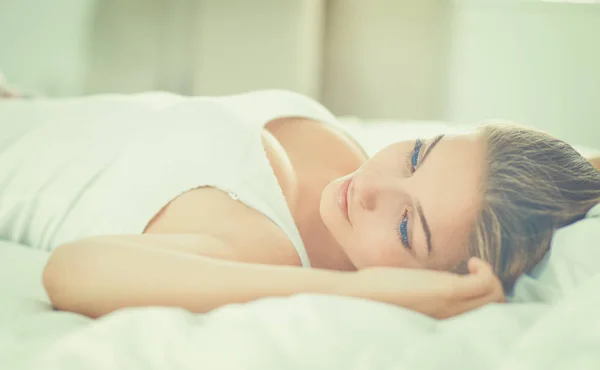 Hermosa joven acostada en la cama cómoda y felizmente — Foto de Stock