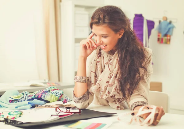 Glimlachende vrouwelijke mode-ontwerper zit aan het bureau — Stockfoto