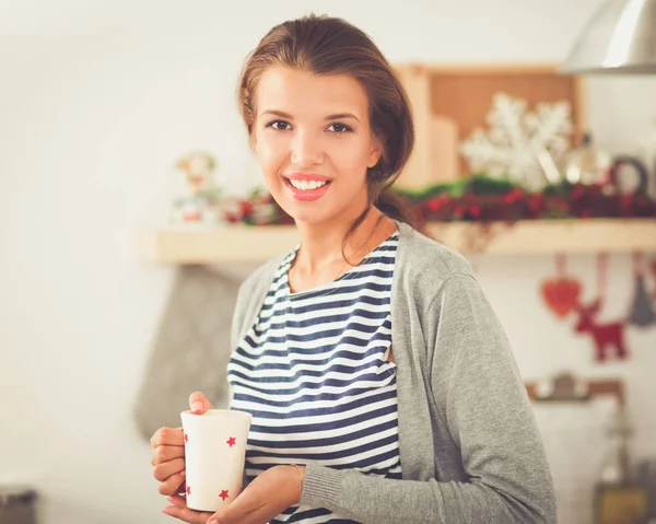 Sorridente giovane donna in cucina, isolata su sfondo natalizio — Foto Stock