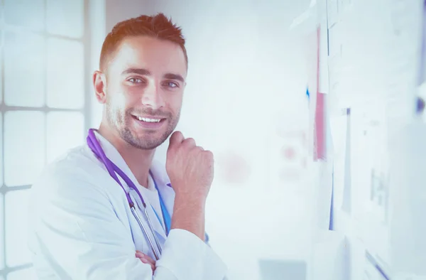 Retrato médico masculino joven y confiado de pie en el consultorio médico. — Foto de Stock