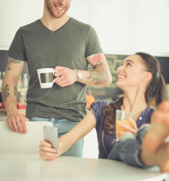 使用智能手机坐在厨房对幸福的夫妇 — 图库照片