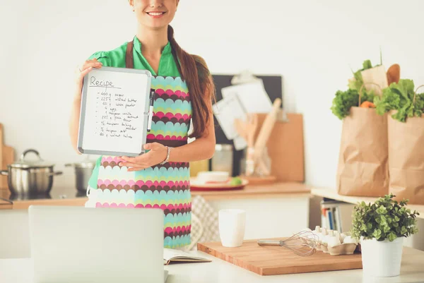 Usmívající se mladá žena v kuchyni, izolované na pozadí — Stock fotografie